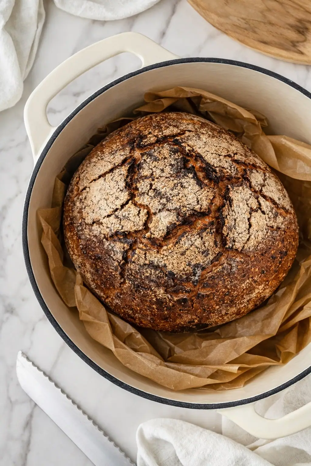 A freshly baked rye loaf in a cast iron pot, lined with baking paper