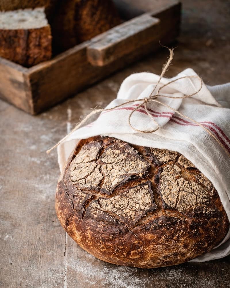 Signature Rye Loaf, wrapped in a linen cloth on a floured board